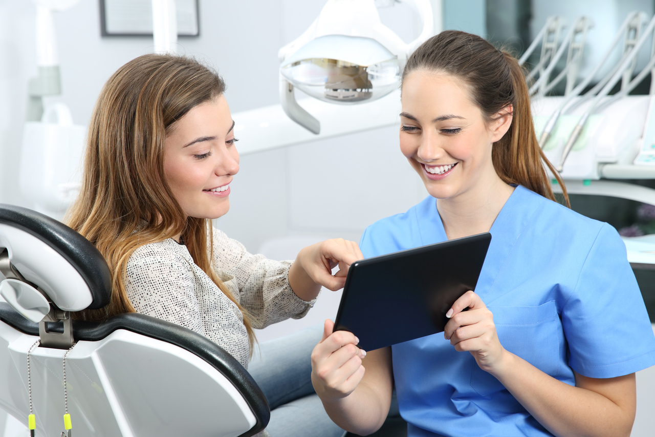 dental hygienist showing digital images to a patient in a dental chair